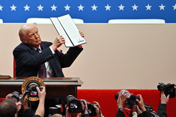 Donald Trump signs executive orders during the inaugural parade inside Capital One Arena, in Washington, D.C., on Monday.