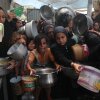 Palestinians, including children, who are struggling to access food due to Israel's blockade and ongoing attacks on the Gaza Strip, wait in line to receive food.
