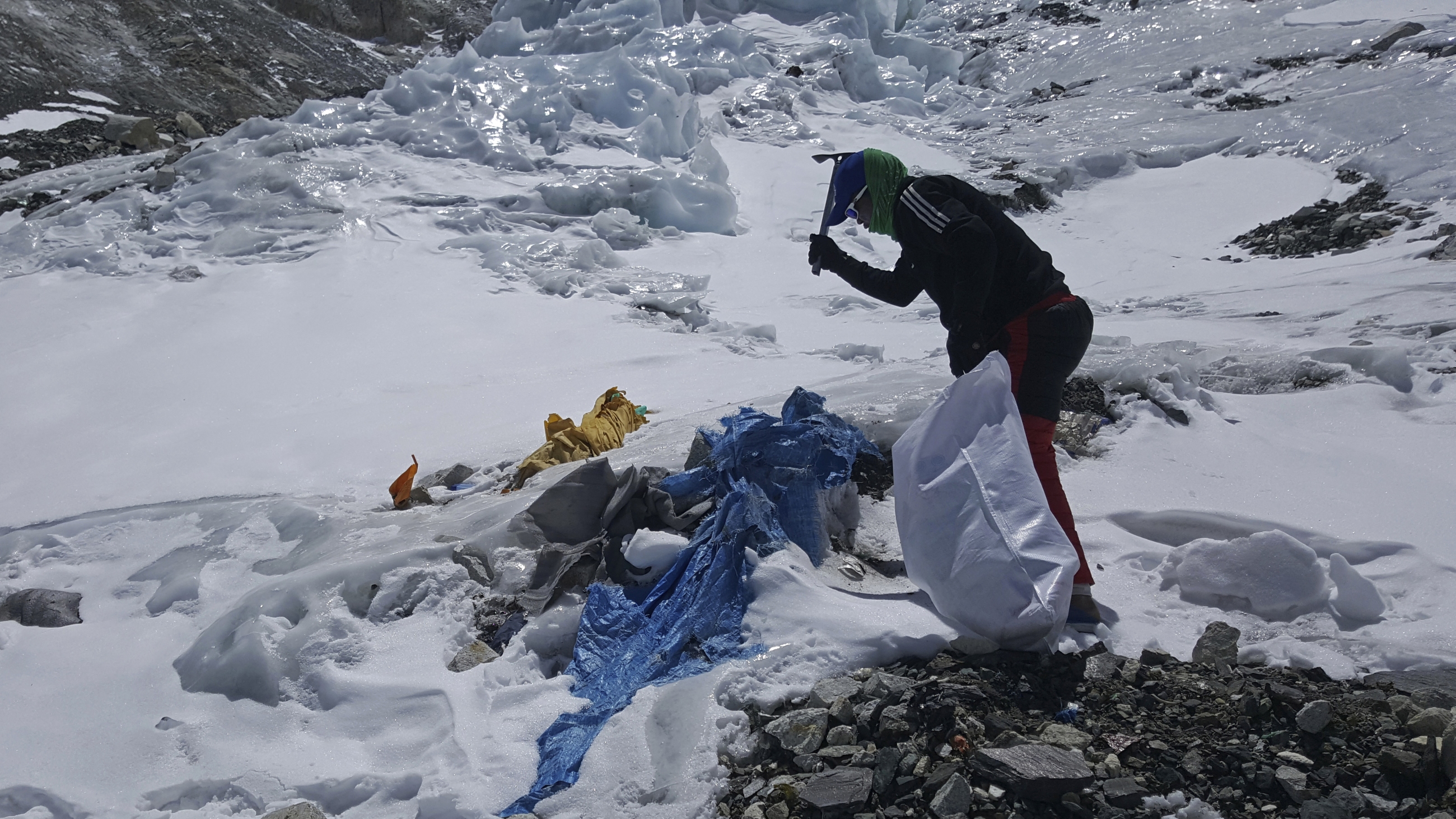 A member of the Nepal government-funded team uses a spade to remove frozen trash on Mount Everest in Nepal in 2021. In the seven decades since Mount Everest was first conquered, thousands of climbers have scaled the peak, and many have left behind more than just their footprints.
