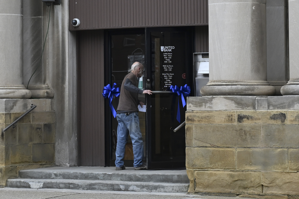A pedestrian walks into United Bank as ribbons in honor of Sarah Beckstrom adorn the door on Main Street in Webster Springs, W.Va. on Dec. 3.