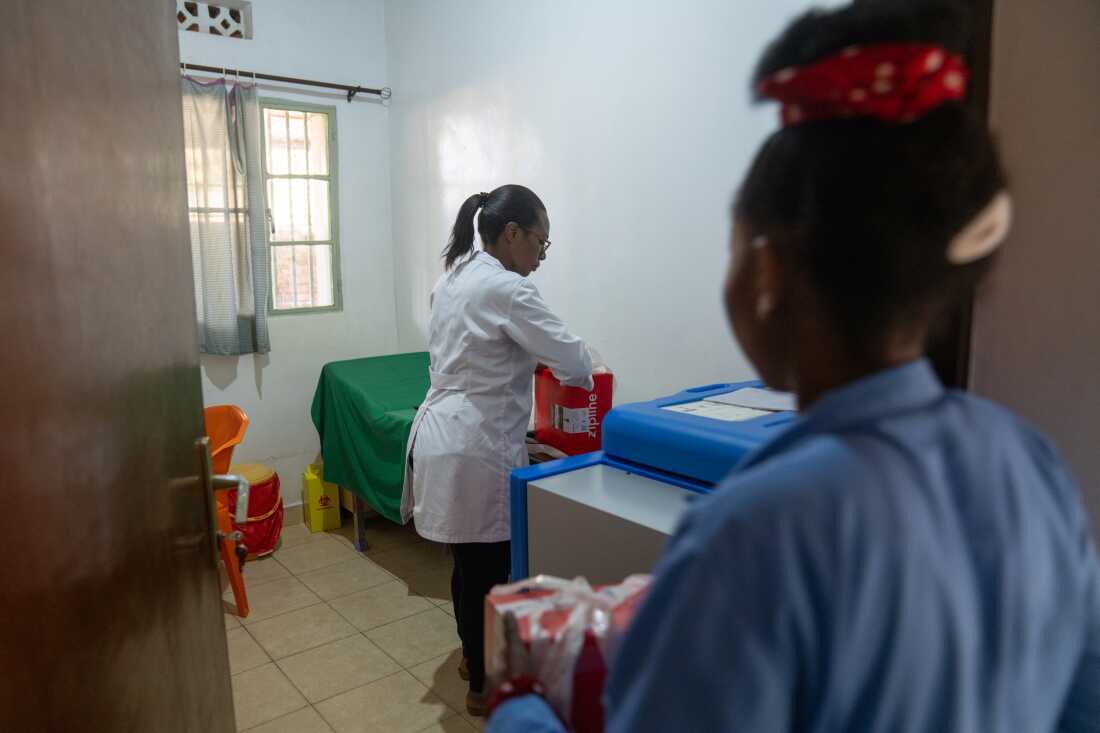 Rosaline Uwere unpacks and puts away the shipment in a solar refrigerator they have at the post for storage.
