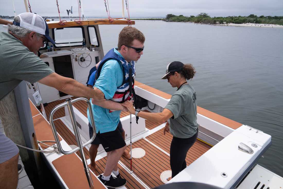 Next Steps staff members help Cody get onto a boat for a ride around the Barnegat Bay in New Jersey.