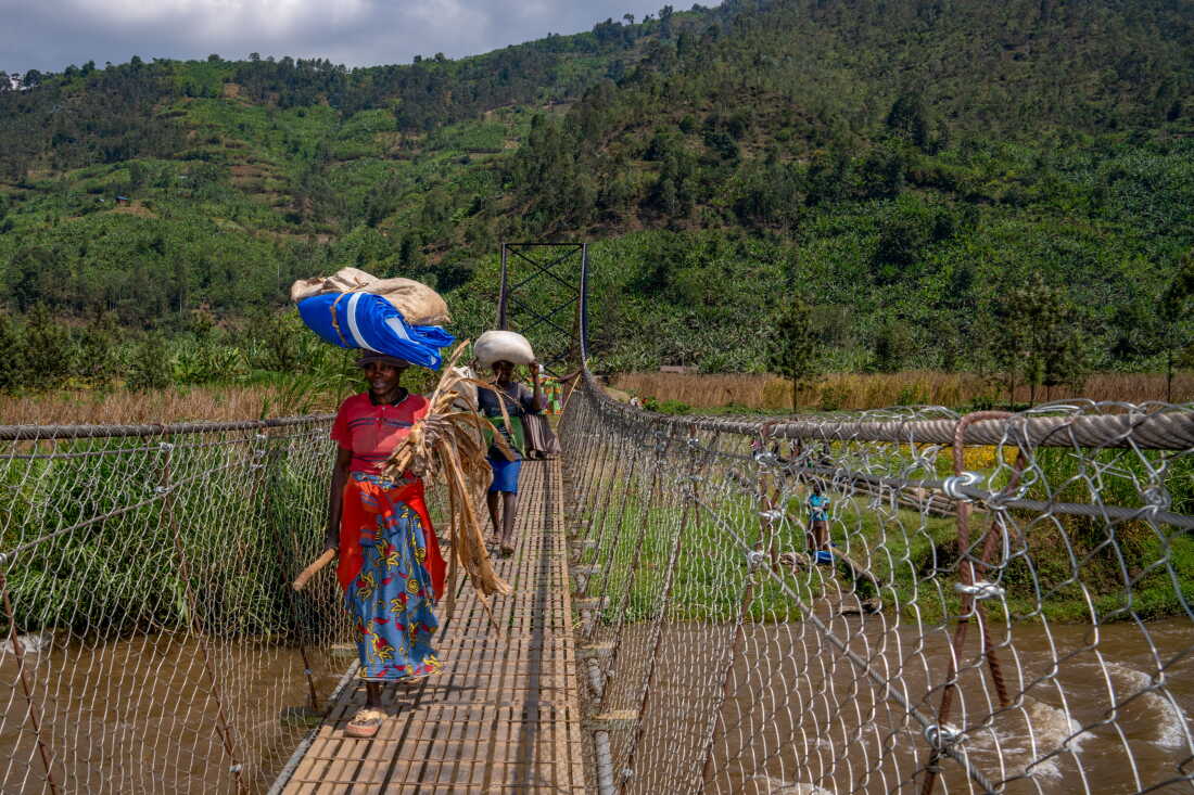 People cross Cyangoga Suspension Bridge that was built by Fika in rural Rwanda. The bridge connects communities that were divided by a rushing river and relied on a ferry system or sometimes dangerous log bridges. Now the shared services like the community health post and the school are much easier to access and crossing even in bad weather is reliable.