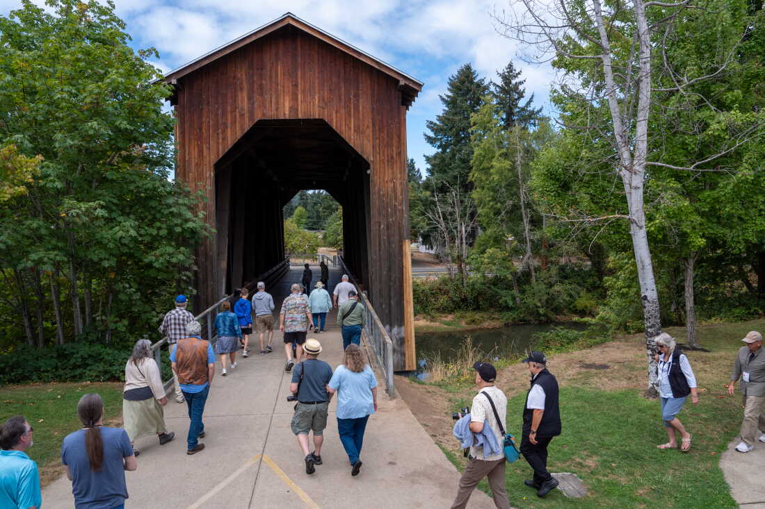 Attendees of the 2026 Buster Keaton Conference cross the Chambers Covered Railroad Bridge during a tour in Cottage Grove, Ore., on Saturday, Aug. 29, 2026. (Krista Rossow for NPR)