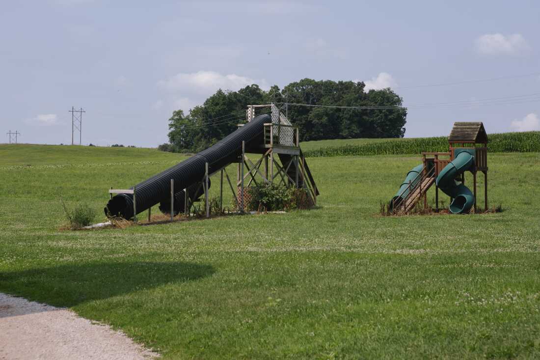 Playground tube slides stand on Smyser’s Farm in a grassy area. One tub slide has a twist in it.