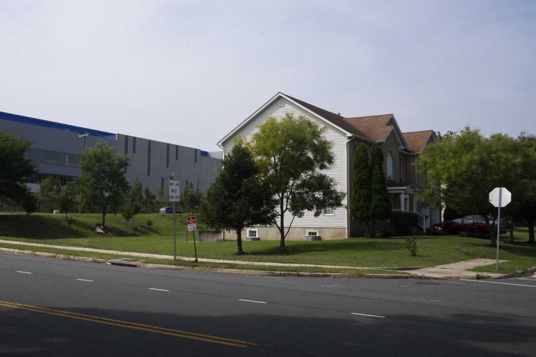 A long Vantage data center building stands behind residential buildings in Sterling, Virginia.