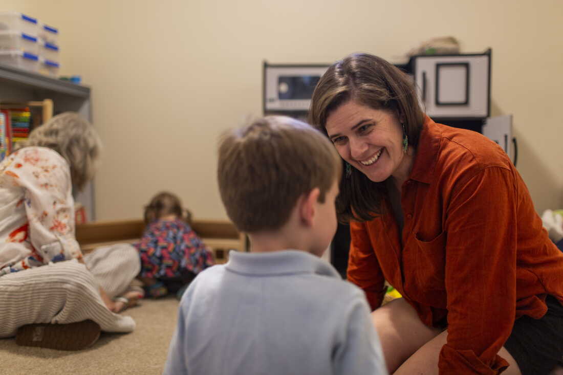 Stacia Bourne sits on the floor, smiling at her son, George, 5, whose back is facing the camera. On the left side of the frame, Bourne's mother, Mary Jo Galusha, sits on the floor with Bourne's daughter, Robin, 23 months.