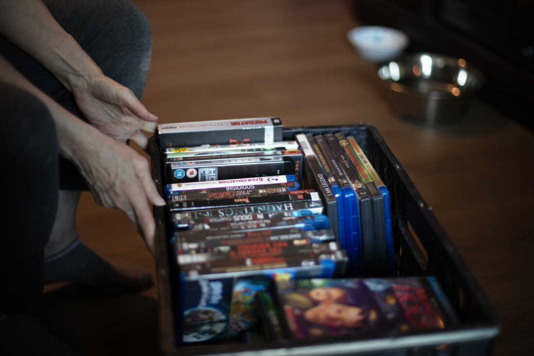 Debbie Willson pulls out a plastic crate filled with movie DVDs that Adam Willson had collected.