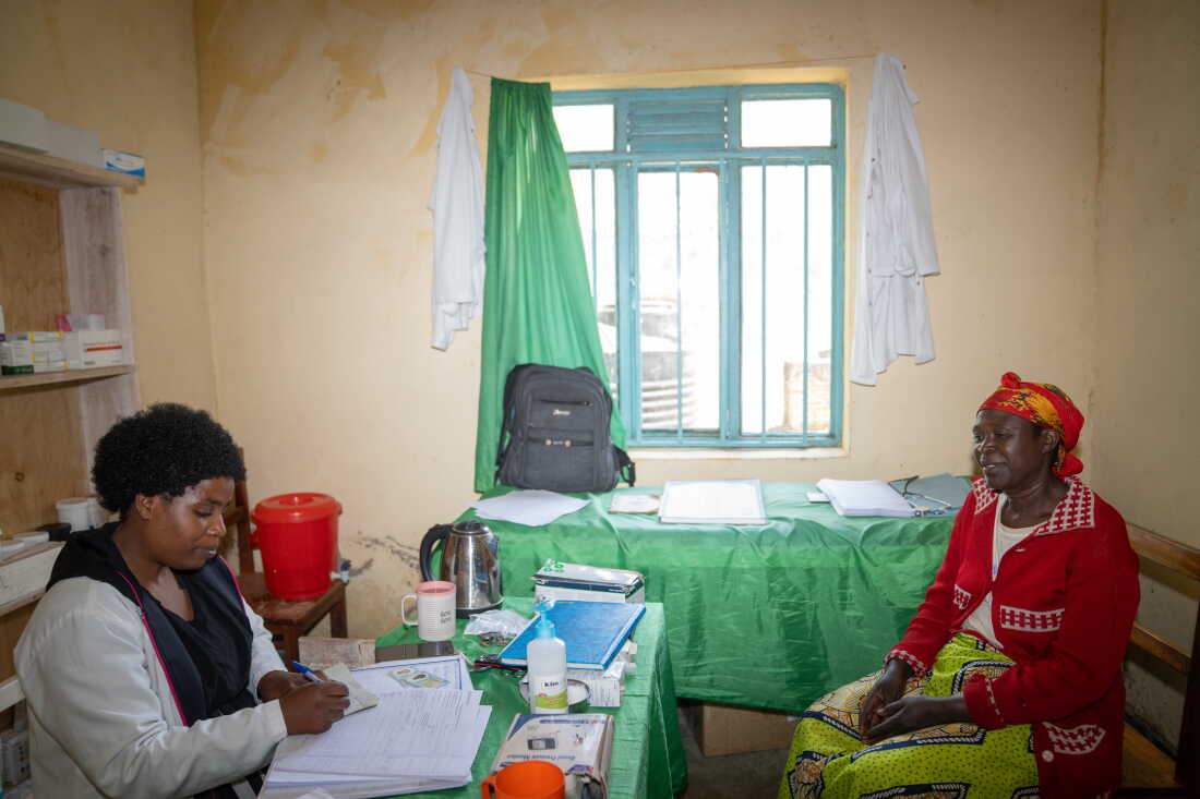 Diane Kwizera, 32, a nurse, meeats with Consolée Uwamaliya, 57, at the health post near the Cyangoga Suspension Bridge. The bridge provides easier access for people to receive care at the post.