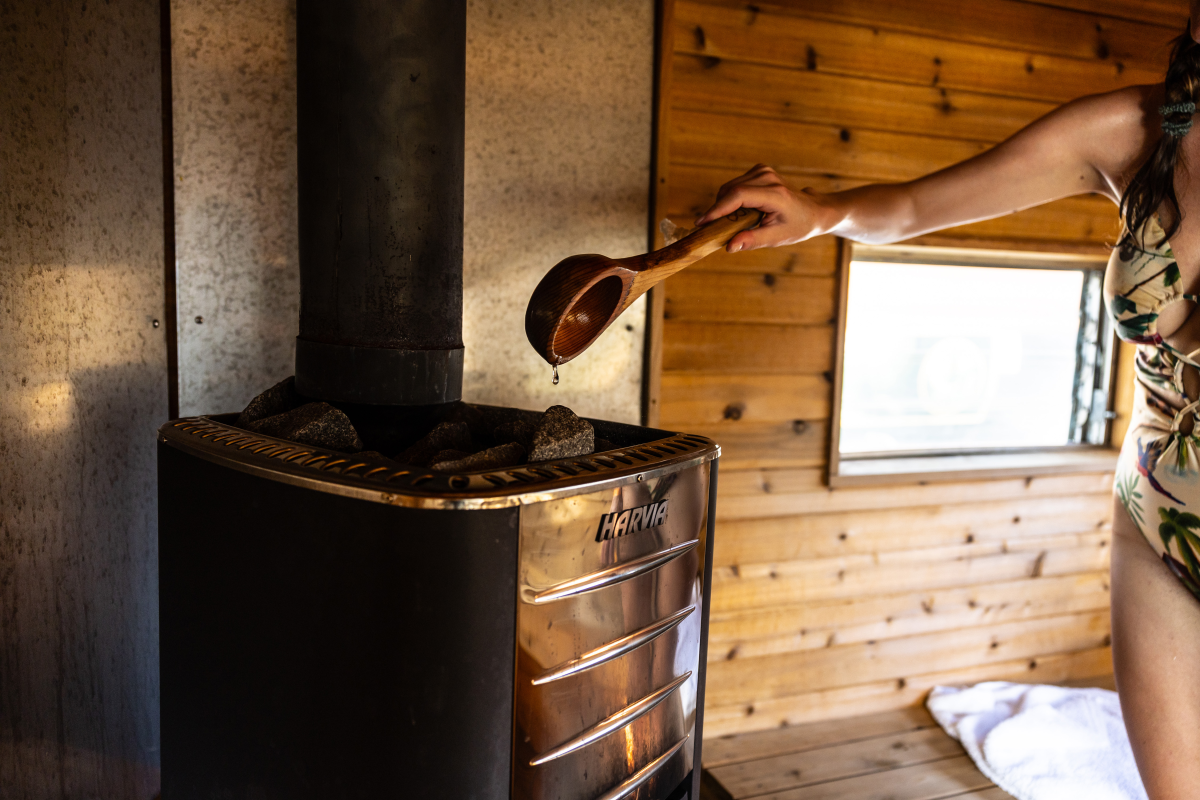 Amanda Morrow, of Seattle, ladles water onto sauna rocks inside a vintage camper trailer-converted sauna during the festival.