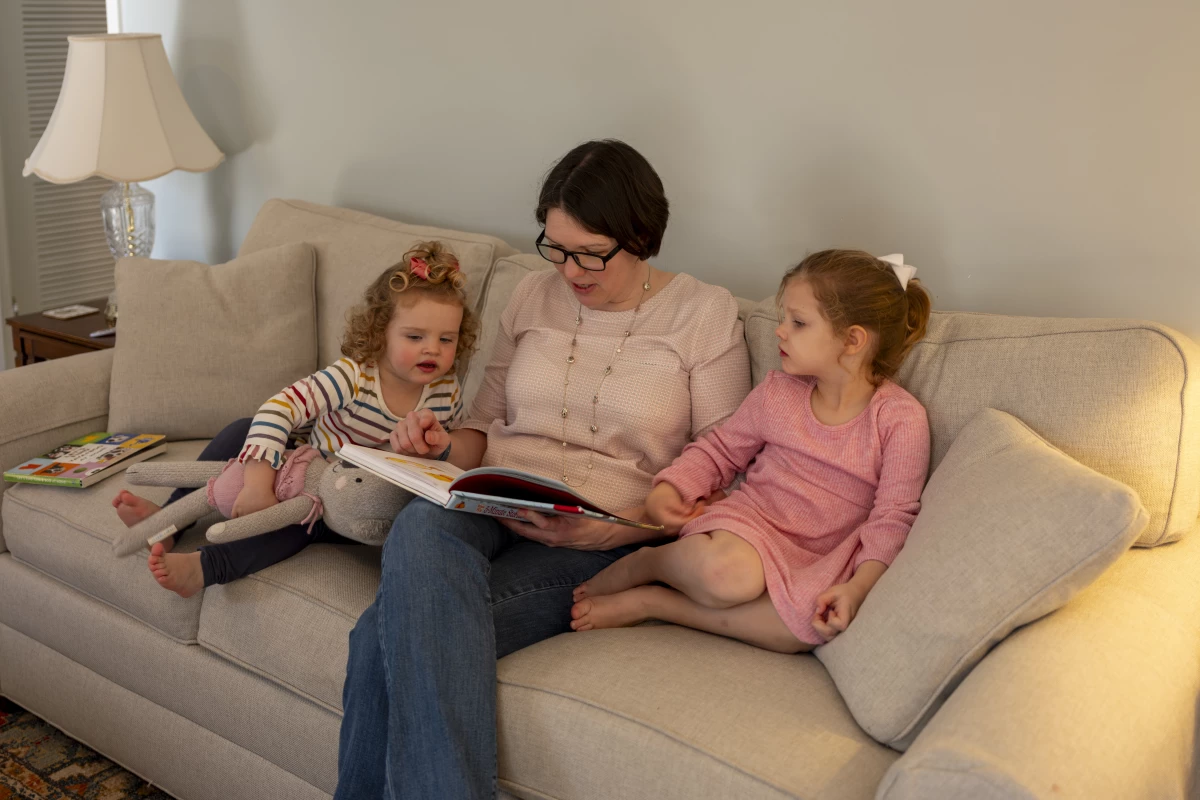 Terry reads to her daughters as they snuggle with her on the couch.