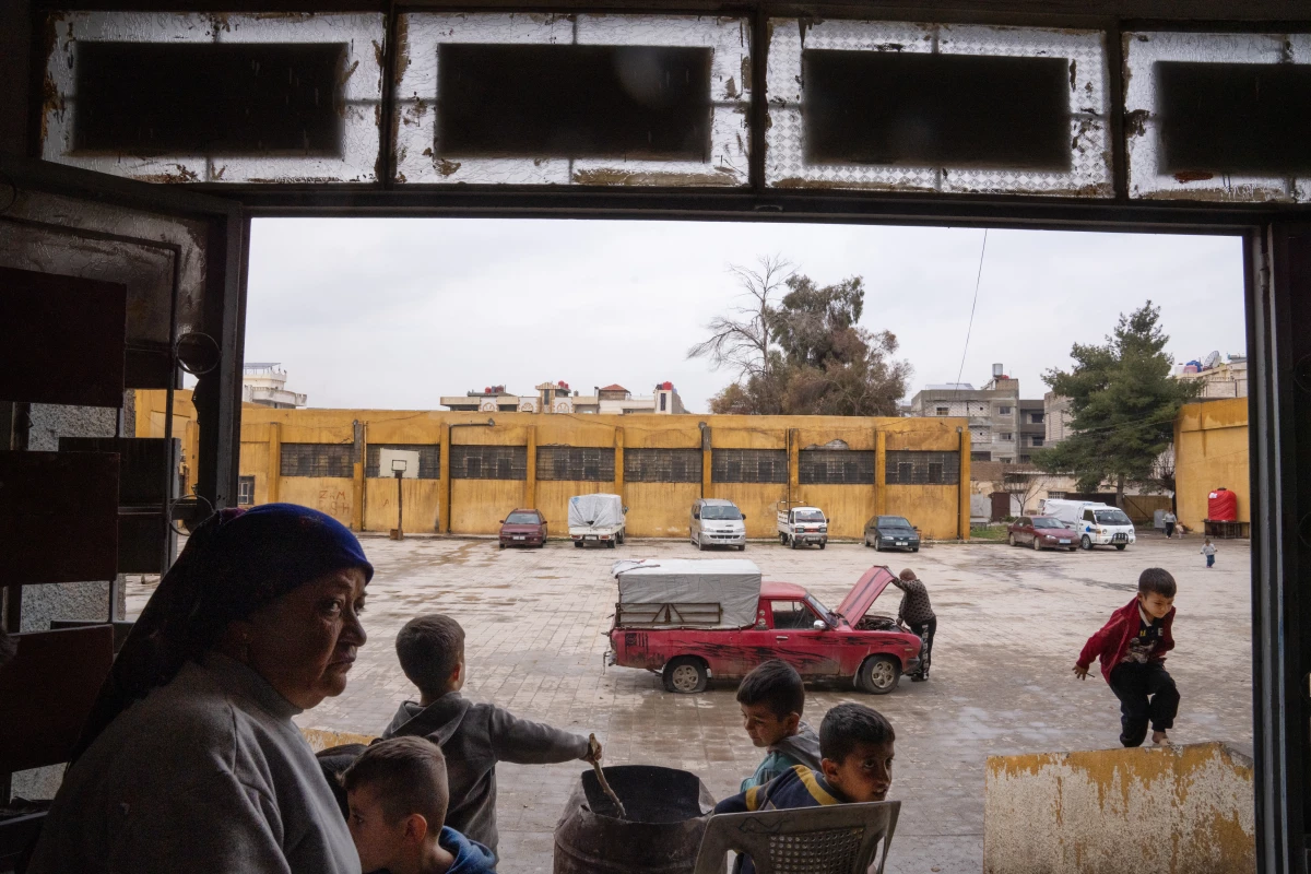 Sabah Hassan Biro (left) stands at the entrance to a vacant school as children play.