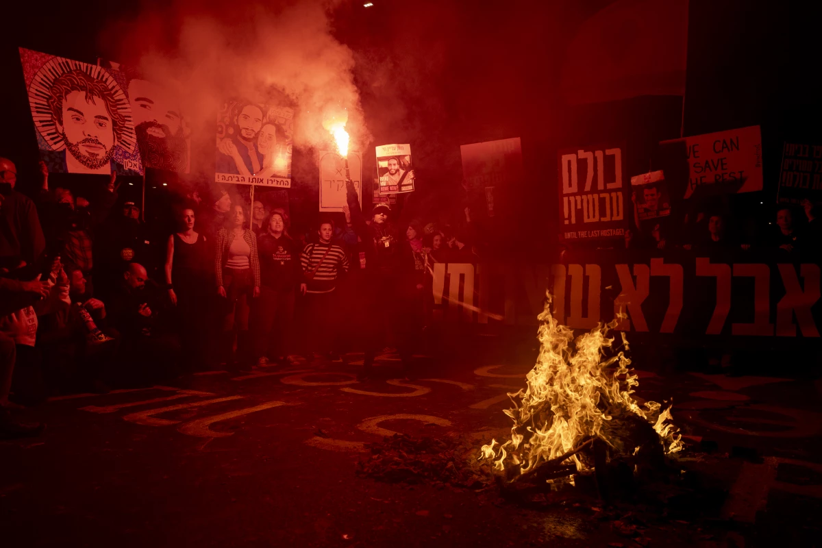 Freed hostage Ilana Gritzewsky holds a smoke torch as protesters set a fire during a demonstration calling for the release of all hostages held by Hamas in Gaza on Saturday in Tel Aviv. Israel's domestic security agency says it now had Hamas' battle plans and other warnings for the Oct. 7, 2023 attacks but failed to take them seriously.