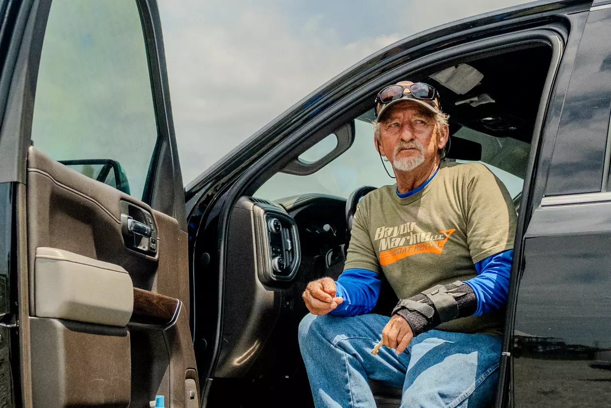 Acy Cooper eats lunch out of his pickup truck at the Myrtle Grove Marina in Port Sulphur, La. on Friday, May 15, 2026. Cooper had just returned to the marina after a shift ferrying oil rig workers from offshore platforms — a job he's taken because of falling shrimp prices and increasing fuel costs.