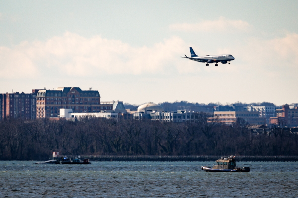A flight flies over law enforcement boats and the partially submerged fuselage of American Airlines Flight 5342 in the Potomac River on Saturday in Washington, D.C.