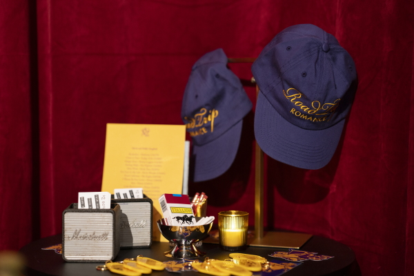 Exit Lane and 831 Stories merchandise — including baseball caps that say "Road Trip Romance", candy cigarettes, keychains — is on display at Grand Baby karaoke bar in New York City.