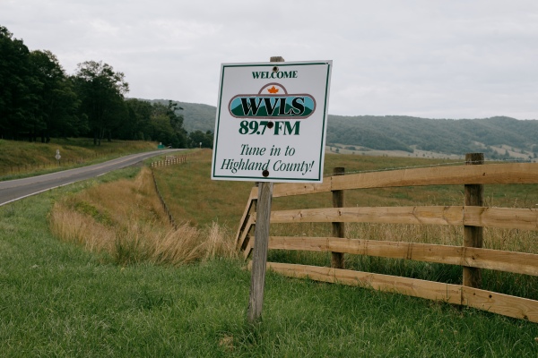 A sign for Allegheny Mountain Radio's WVLS 89.7 FM stands along U.S. Route 250 in Hightown, Virginia, a small town situated in a valley to the west from Monterey, Virginia, on Friday, July 18th, 2025. Credit: Kristian Thacker for NPR