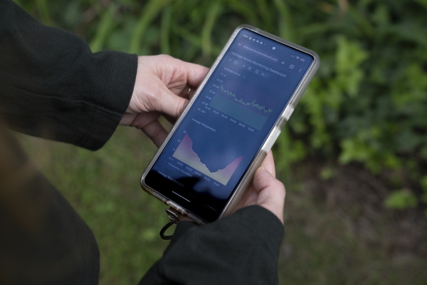 This photo shows a smartphone that's held in the hands of Kasey Hatch. Its screen shows two graphs that display the levels of noise measured in the area near the Vantage data center in Sterling.