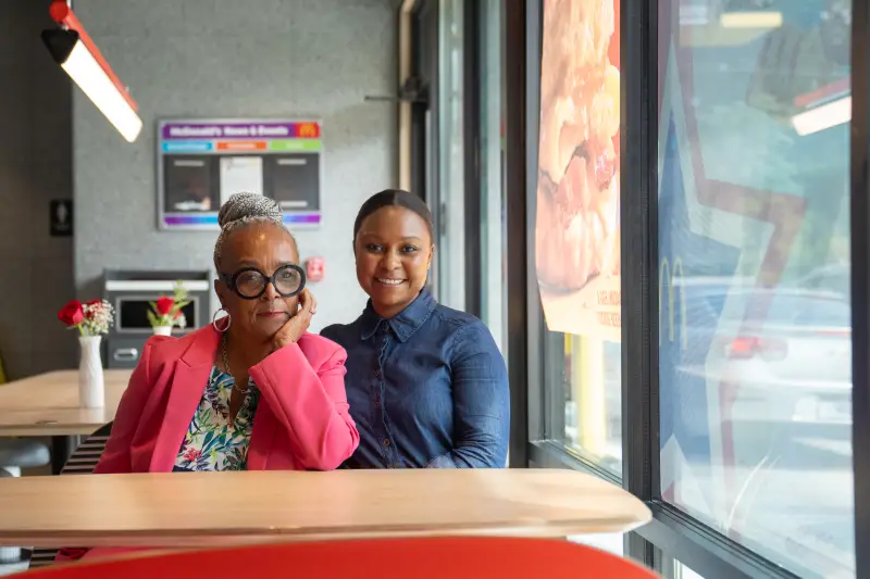 Mary Hopkins Navies (no hyphen) and her daughter Imani Ford sit at a table inside one of the McDonald's restaurants they own in Prince George's County, Md.