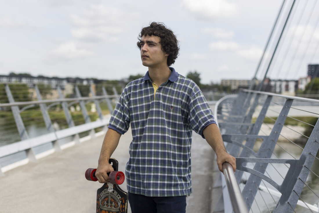 Launderville stands on a bridge while holding a skateboard.
