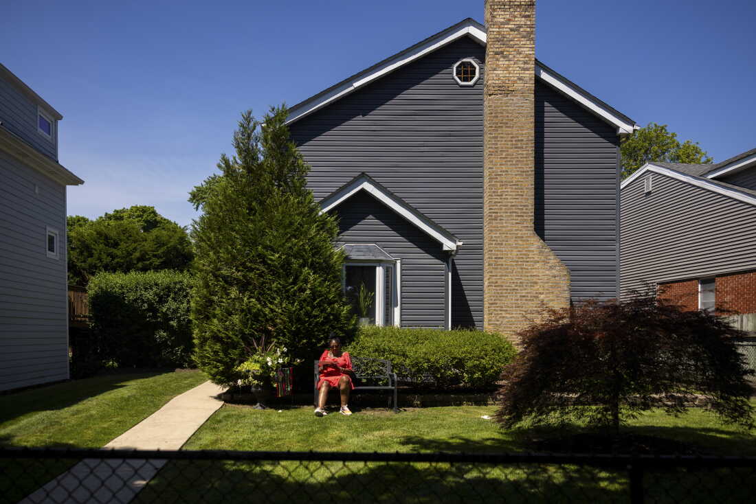 Kimberly Holmes-Ross sits on a bench on a grassy yard outside her home in Evanston, Illinois.