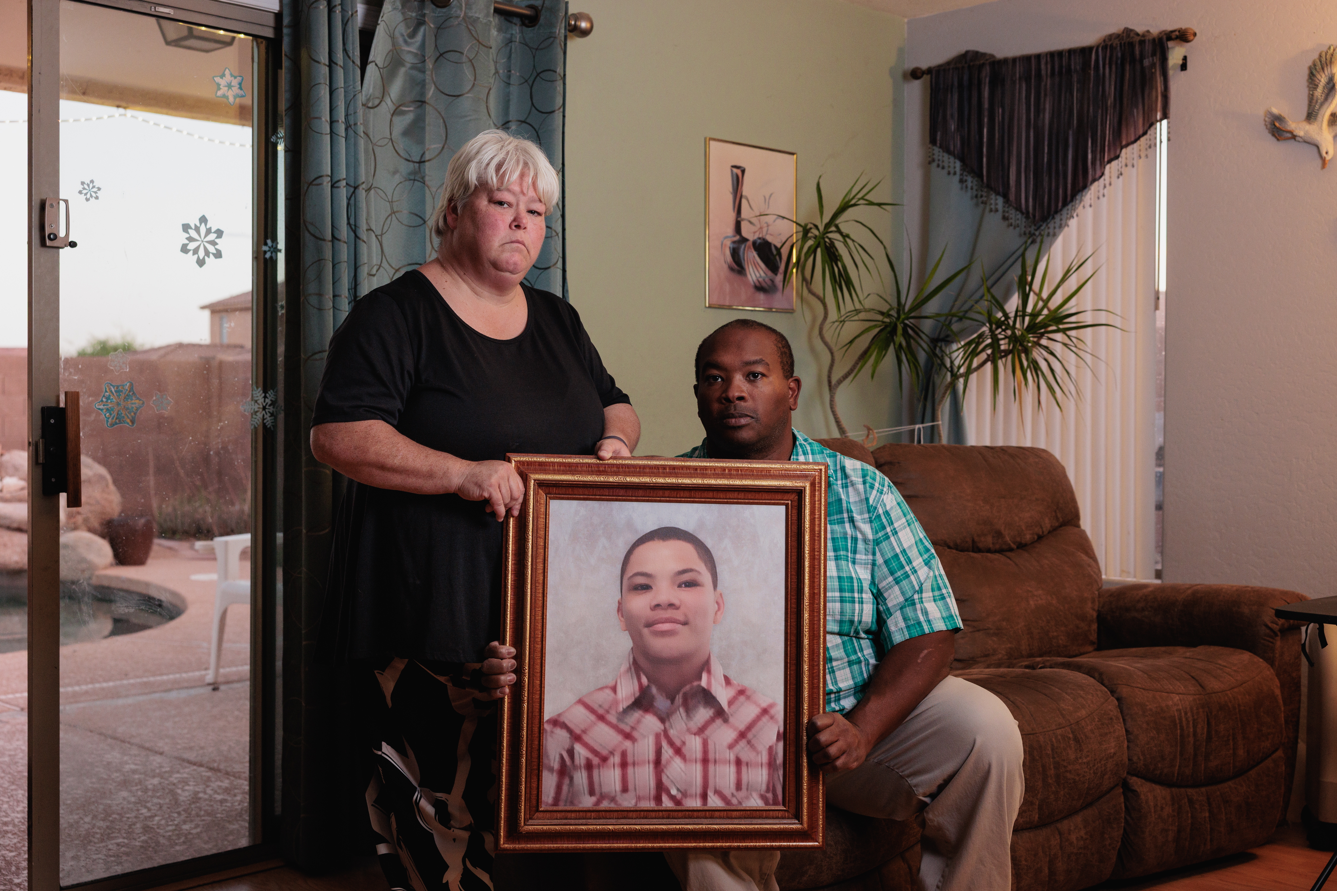 Bobbie (left) and DeForrest Williams hold a portrait of their son, Christian Williams, at their home in Buckeye, Ariz. Christian died at age 15 of diabetes complications while in a residential foster care program.