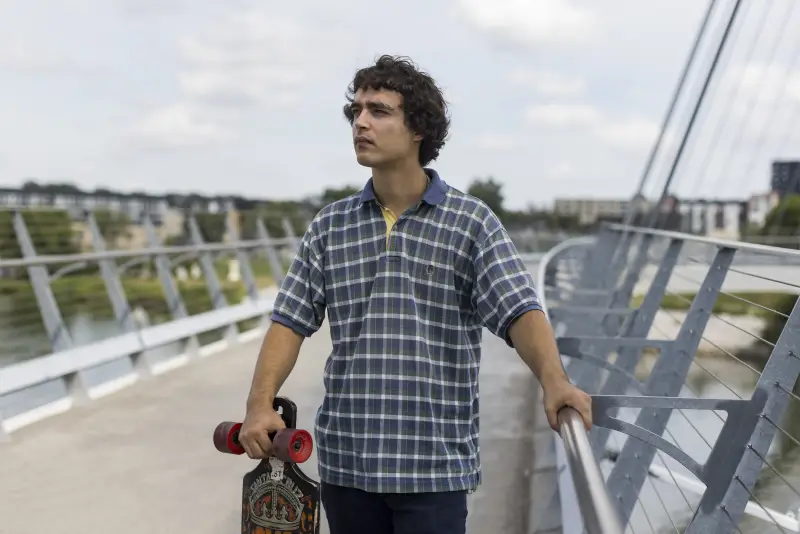 Launderville stands on a bridge while holding a skateboard.