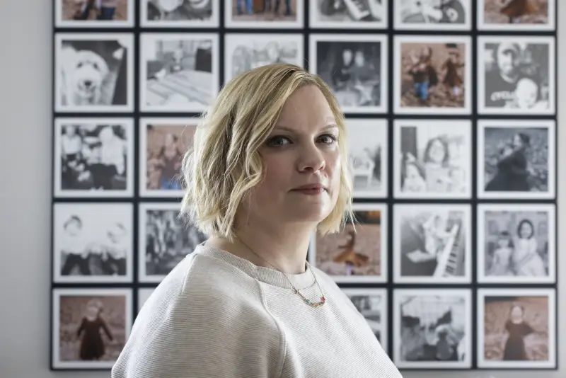 Marlatt stands in front of a grid of framed family photos.