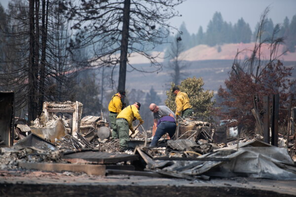 Firefighters and residents dig through debris on Tuesday after a wildfire destroyed homes in a neighborhood in Spokane, Wash.