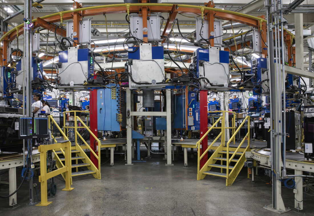 Workers assemble GE products on a platform that is shaped like a semi-circle.