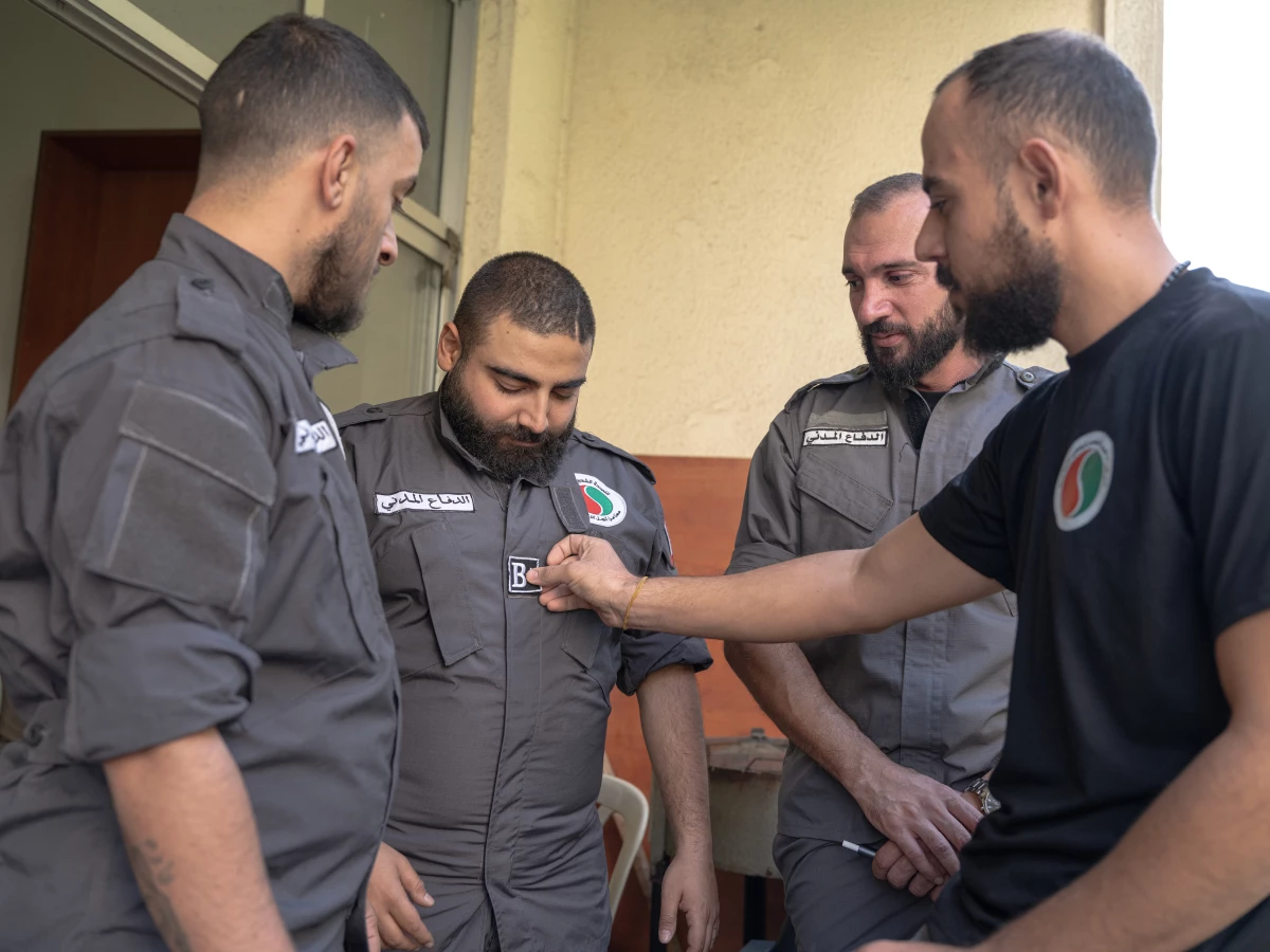 Jad Deeb, center, and other first responder volunteers talk on the balcony of their office in Beirut. One of his colleagues affixes a patch to Deeb's shirt, indicating his blood type.