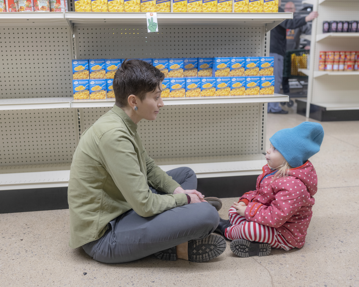 Kelly Hatas, executive director of Hocking Athens Perry Community Action (HAPCAP), talks with the child of a couple who are shopping at the food pantry. Hatas says the nonprofit has had to scramble all year as various safety-net programs were hit with federal funding cuts or pauses.