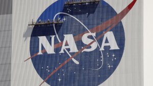 Workers on scaffolding repaint the NASA logo near the top of the Vehicle Assembly Building at the Kennedy Space Center in Cape Canaveral, Fla., May 2020.