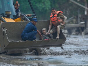 Rescuers use an earthmover to carry a victim of flash flooding to safety along the Trishuli River in Nepal's Nuwakot district.