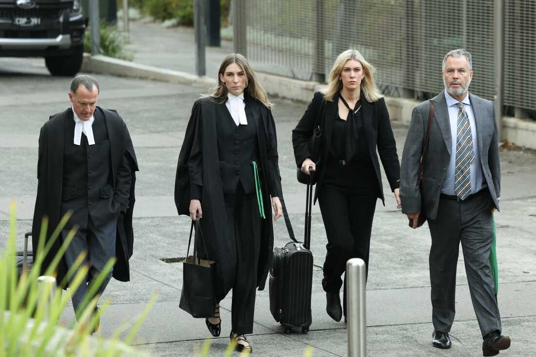 Four lawyers walk outside a courtroom.