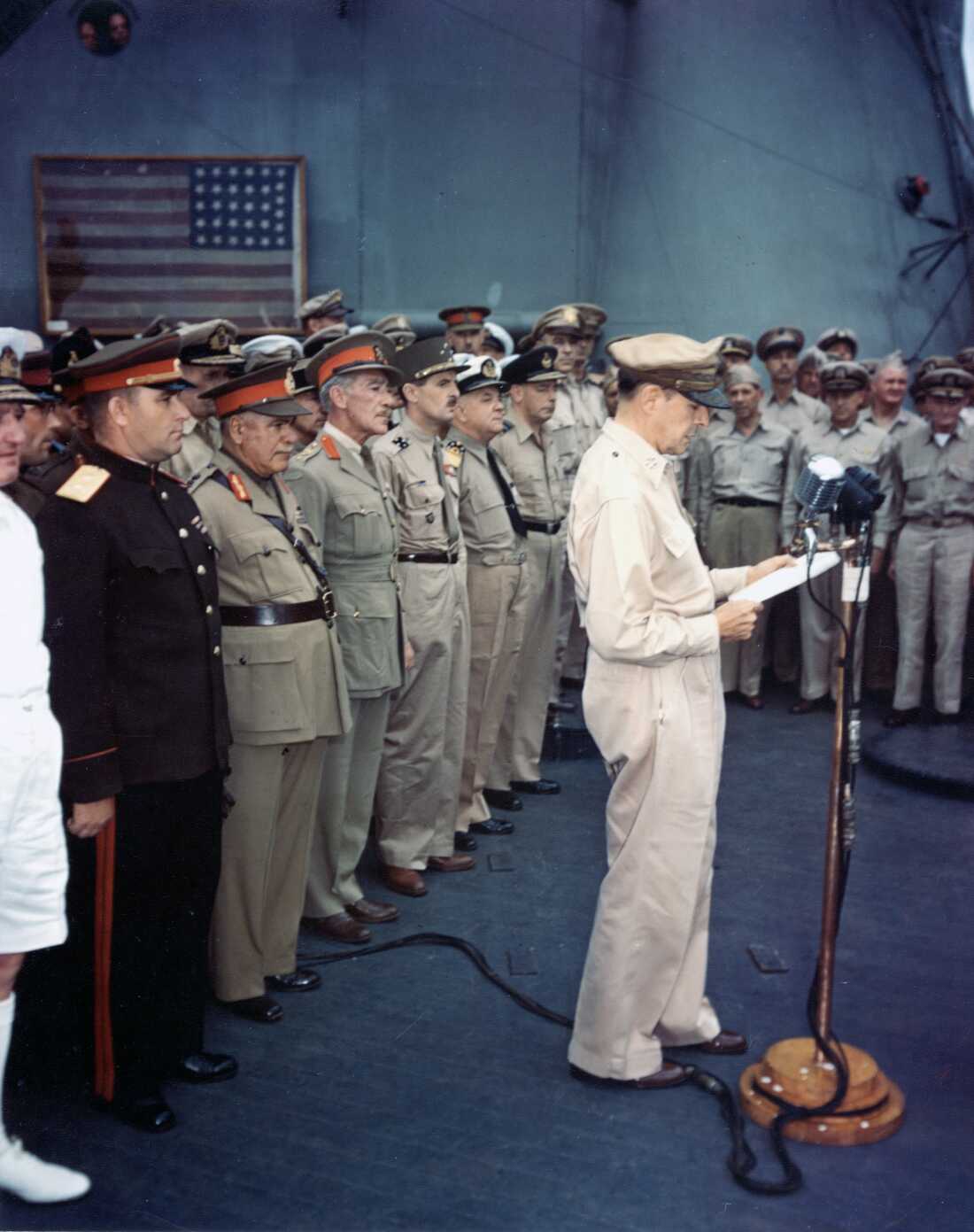 United States Army Gen. Douglas MacArthur reads his speech to open the surrender ceremonies on board USS Missouri on Sept. 2, 1945. Allied representatives are behind him, including Col. Lawrence Cosgrave.