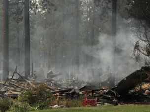 A burned structure smolders due to a wildfire, on Aug. 2, 2026, in Spokane, Wash.