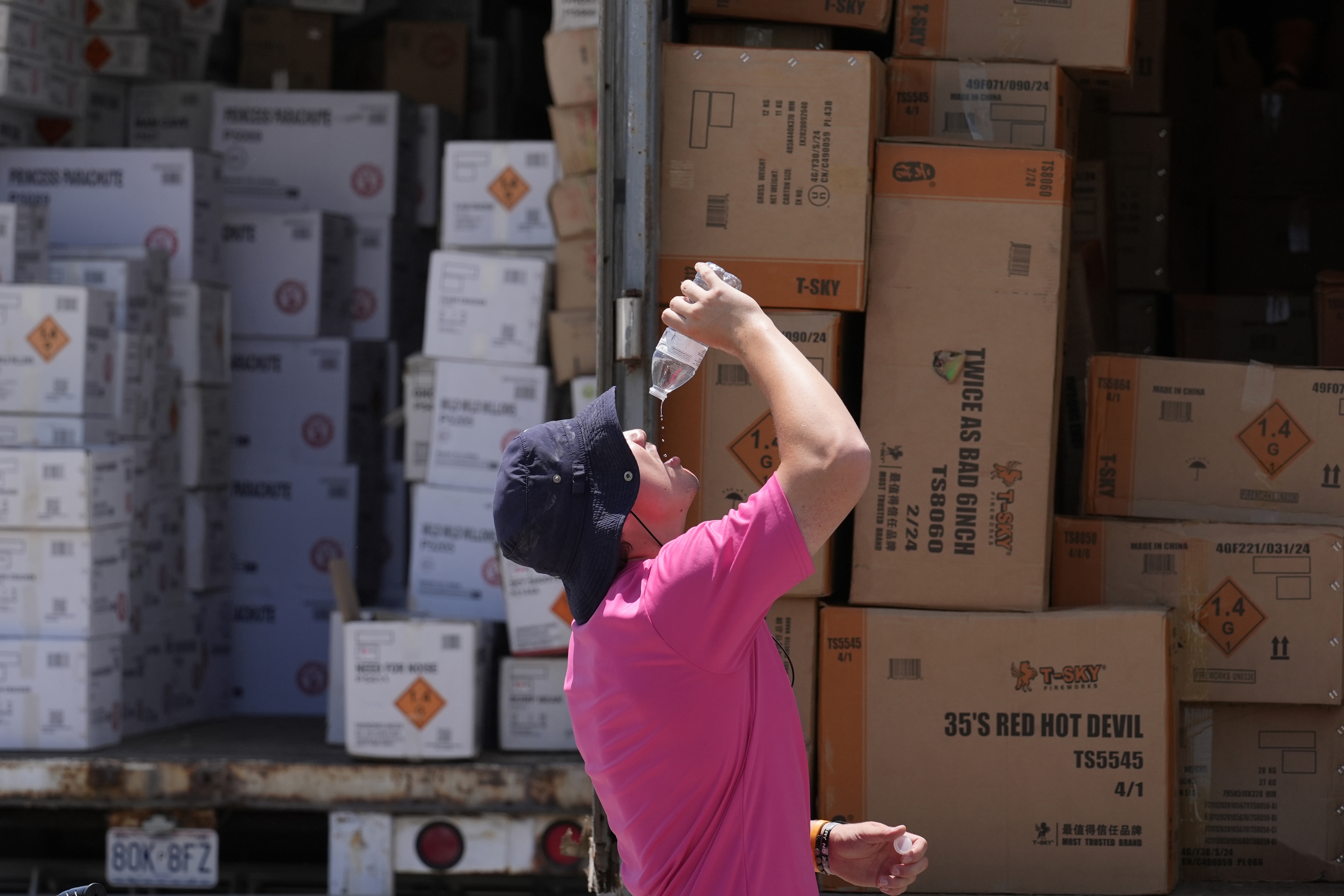 Wyatt Seymore pours the last drops of liquid from a water bottle into his mouth on June 17 as he takes a break from unloading a stiflingly hot trailer of fireworks outside Powder Monkey Fireworks ahead of the opening of the stand in Weldon Spring, Mo.  (AP)