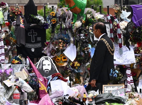 Birmingham Mayor Zafar Iqbal views the tributes at Black Sabbath Bench and Bridge prior to Ozzy Osbourne's funeral procession Wednesday.
