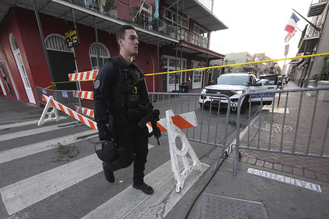 A member of the emergency services walks past a police barricade after a vehicle drove into a crowd on New Orleans' Canal and Bourbon Street.