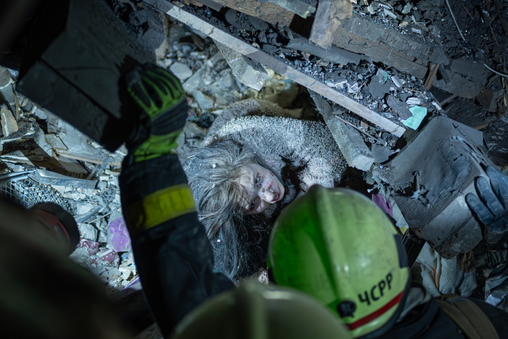 A Ukrainian woman looks at rescuers as they try to pull her out from under the rubble of a building after a Russian military strike on Kyiv, Ukraine, on Thursday. The strike occurred at 1 a.m., when most people were asleep. So far, nine people have been confirmed dead and more than 70 injured. The rescue operation is ongoing.