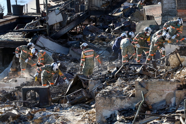 An urban search and rescue team from Mexico combs through the ruins of a beachfront house searching for victims in the aftermath of the Palisades Fire in Malibu, Calif., on Tuesday.