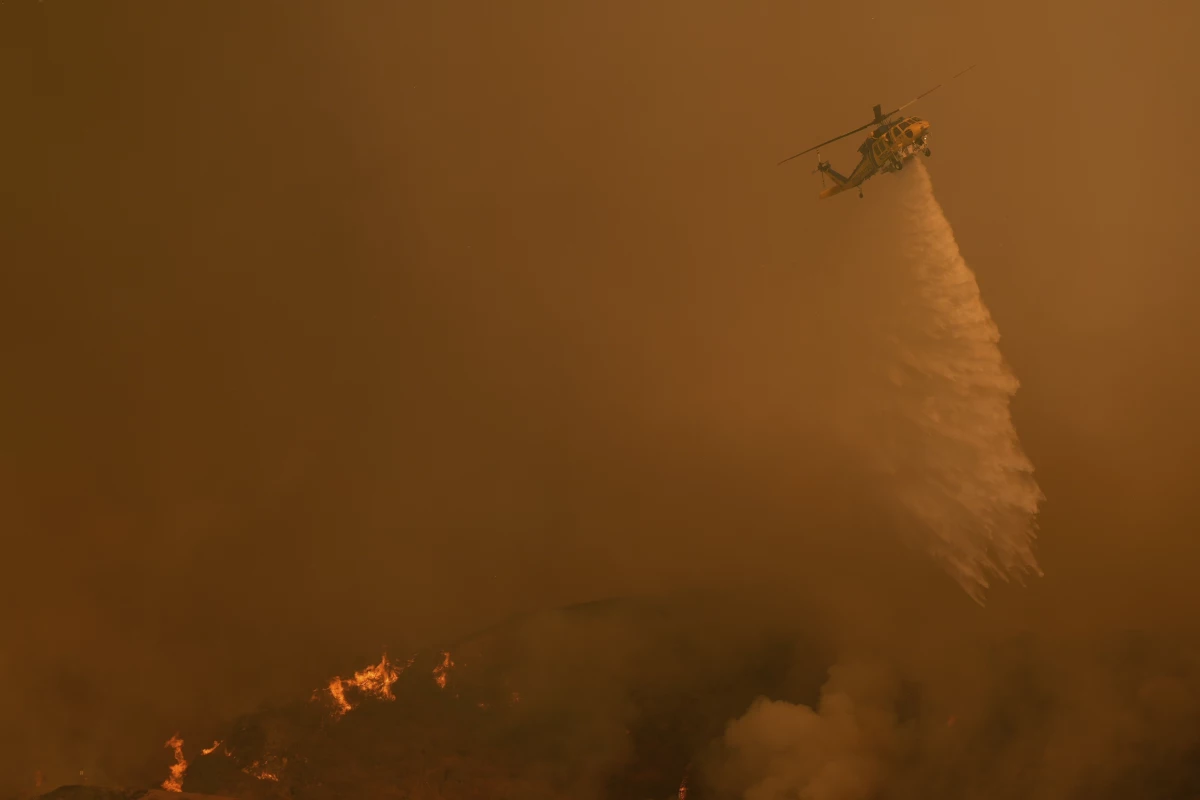 Water is dropped on the Palisades Fire by helicopter in Mandeville Canyon on Saturday in Los Angeles.