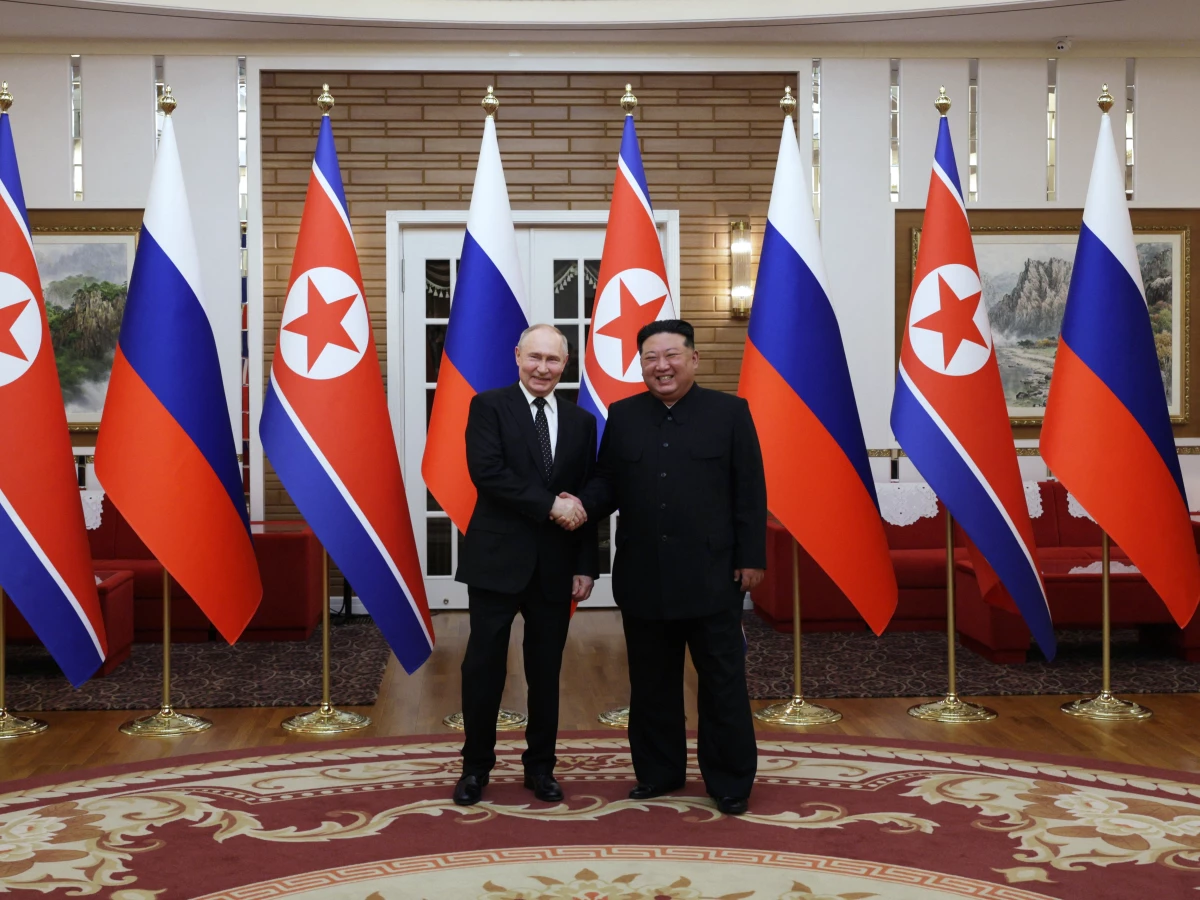 In this pool photograph distributed by the Russian state agency Sputnik, Russia's President Vladimir Putin shakes hands with North Korea's leader Kim Jong Un during a meeting in Pyongyang on June 19