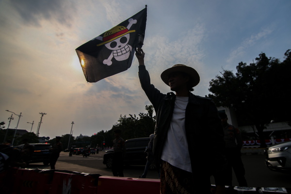 A number of human rights activists carry posters and wave the Straw Hat Pirates' Jolly Roger flag from the anime One Piece during the 873rd Kamisan Action in Jakarta, Indonesia, on August 14, 2025.