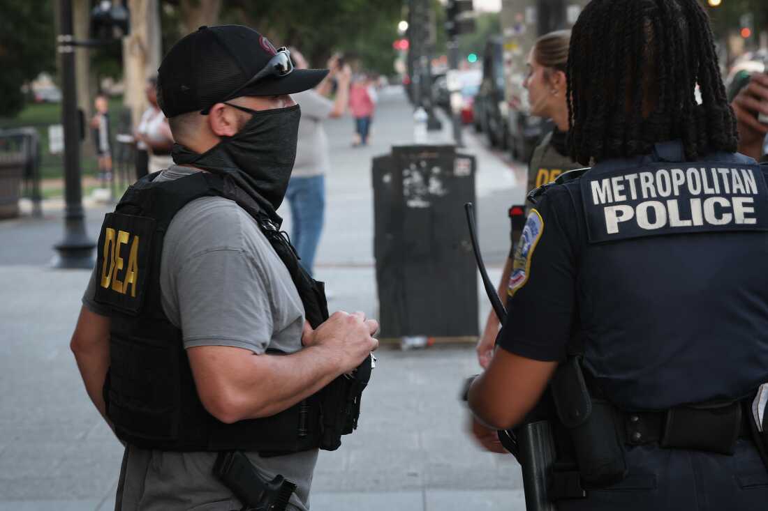 A U.S. Drug Enforcement Administration (DEA) agent talks with a Metropolitan Police Department officer while patrolling near the Washington Monument on the National Mall on August 11, 2025. President Trump announced a federal takeover of D.C. Metro police and mobilization of the National Guard, saying the moves are necessary to restoring order in the city.