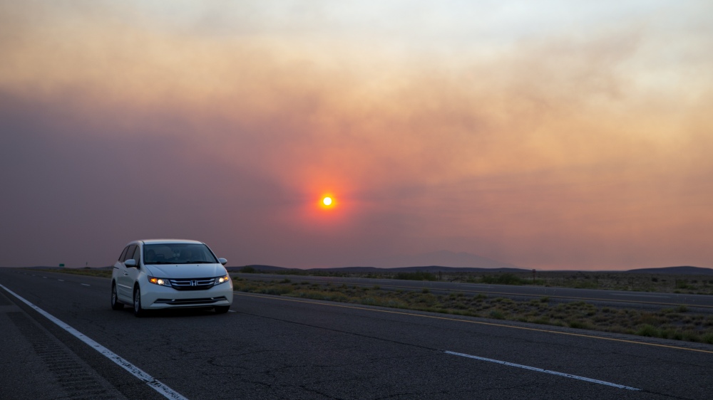 A car rides on the road to Roswell, N.M., as smoke from a wildfire partially blocks the sun near the village of Ruidoso, N.M., on Tuesday, June 18. Thousands of southern New Mexico residents fled the mountainous village as a wind-whipped wildfire tore through homes and other buildings.  (AP)