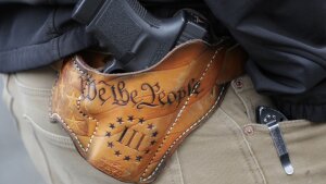 An attendee at a gun rights rally open-carries his gun in a holster that reads "We the People," from the Preamble to the U.S. Constitution, in this 2019 photo at the Capitol in Olympia, Wash.