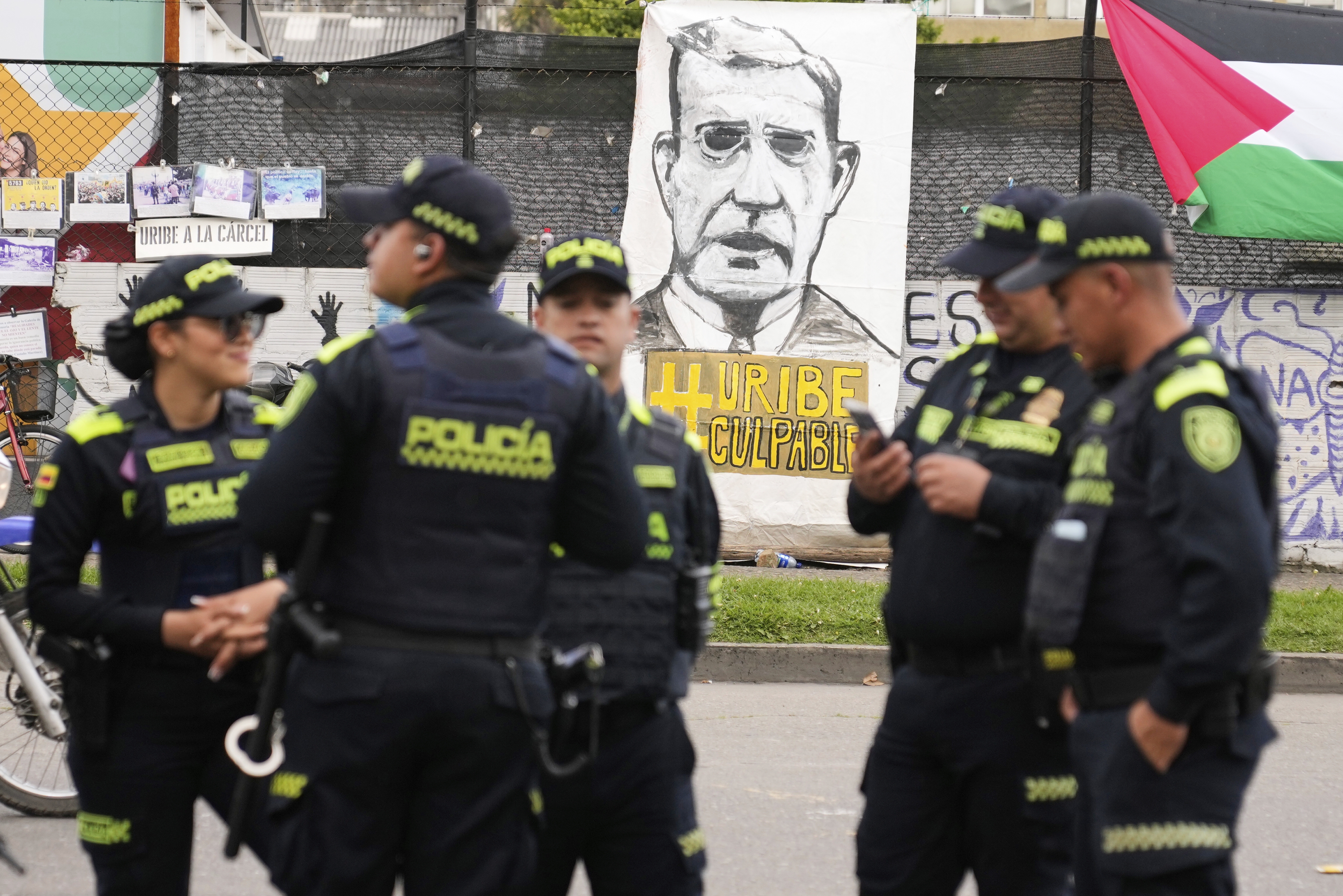 Police stand in front of a banner reading in Spanish "Uribe guilty" displayed by opponents of former President Alvaro Uribe outside the court where a verdict is expected in his trial for witness tampering in Bogota, Colombia, on July 28, 2025.