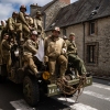 Enthusiasts wearing replica WWII military attire ride atop a WWII-era military truck in Saint-Côme-du-Mont, northwestern France, on June 4, 2024, as part of the